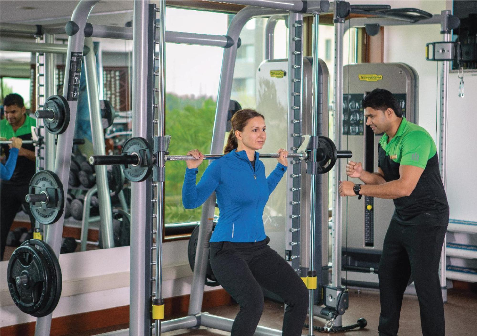 Jumeirah Messilah Beach Kuwait 쿠웨이트 외부 사진 A personal trainer assisting a woman with a weight training exercise